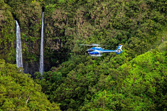 A helicopter turning above the waterfalls of the Kauai interior